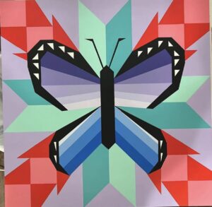 Geometric low-poly barn quilt of a butterfly with teal, purple, red, and pink wings on a patchwork triangle background.